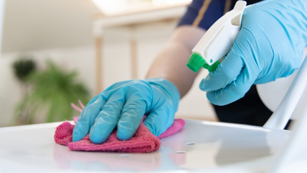 Professional maid service sanitizing a countertop in residence.
