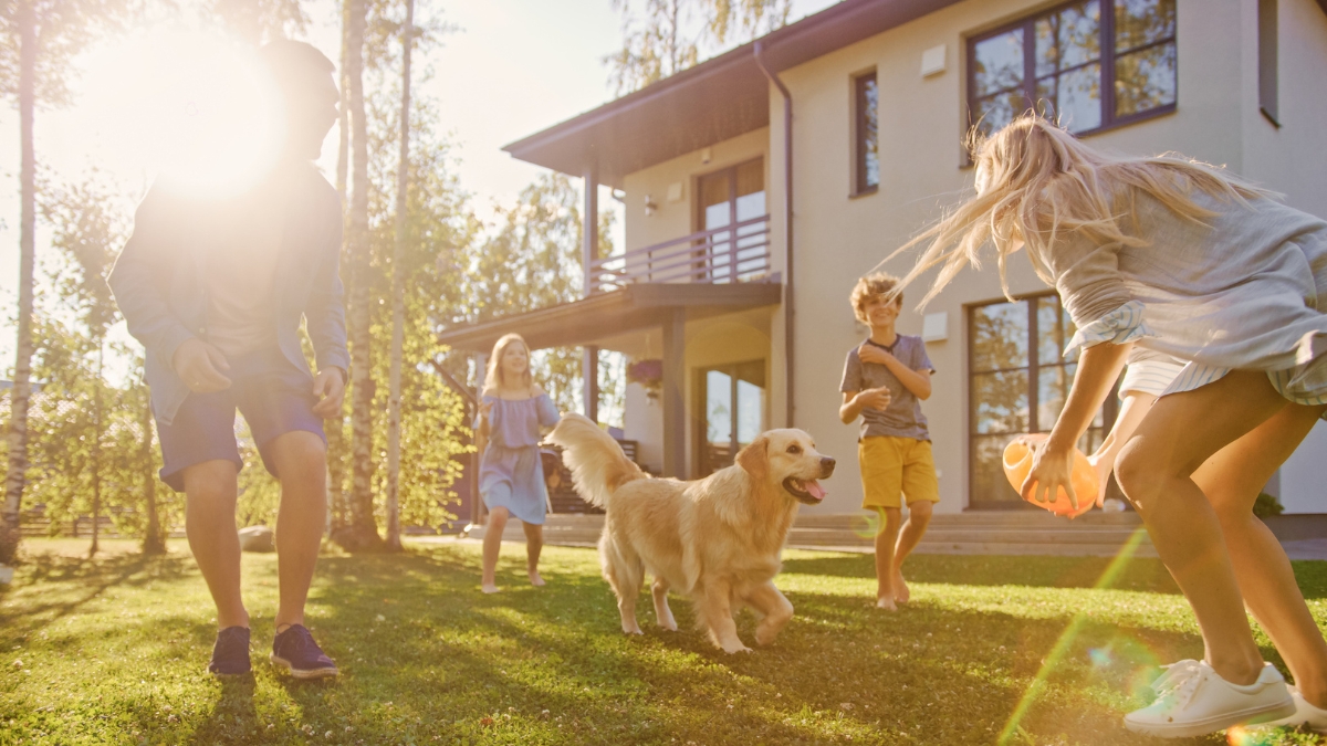 Children and parents playing with their dog outside a well-kept home with maid service.